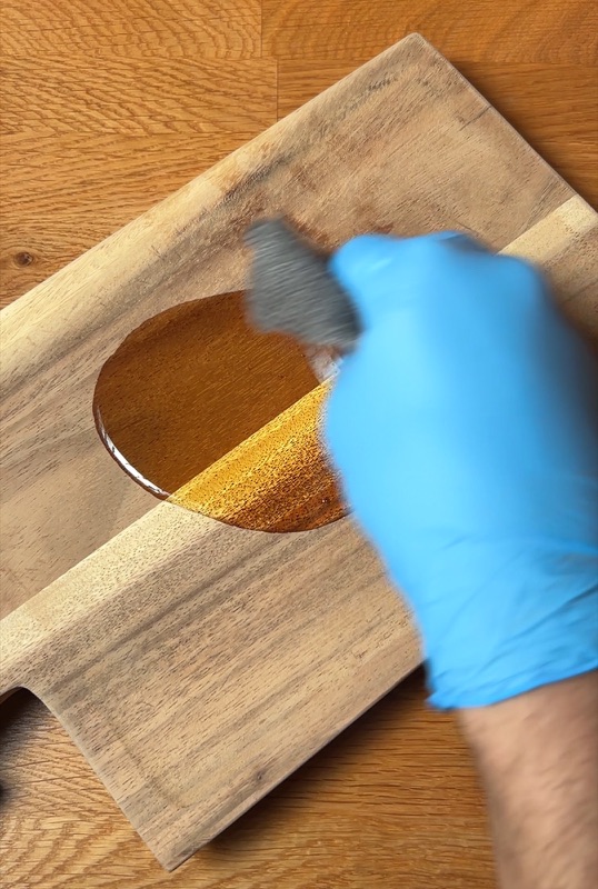 Pflegeprodukt wird dünn auf eine Holzoberfläche aufgetragen