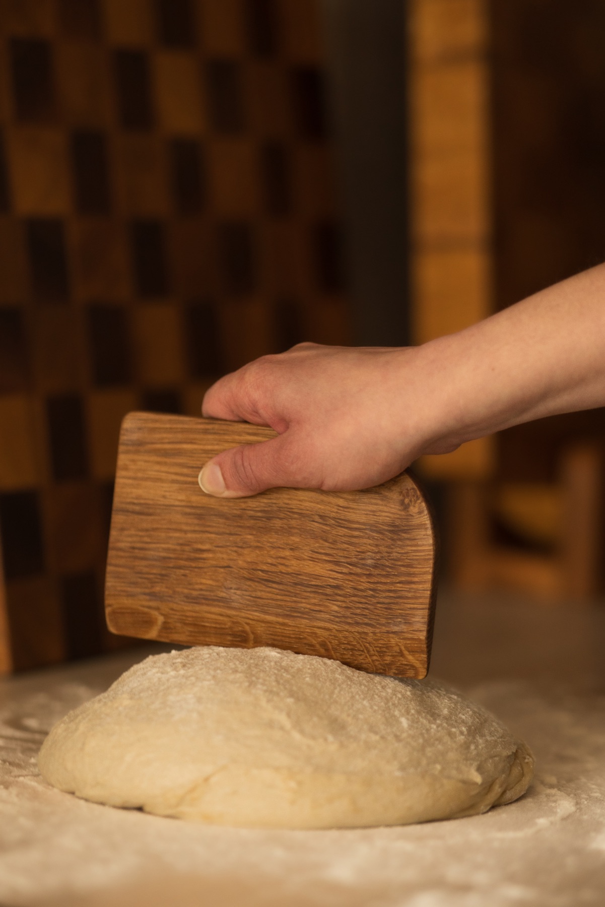Handcrafted oak dough scraper used with sourdough on a floured worktop